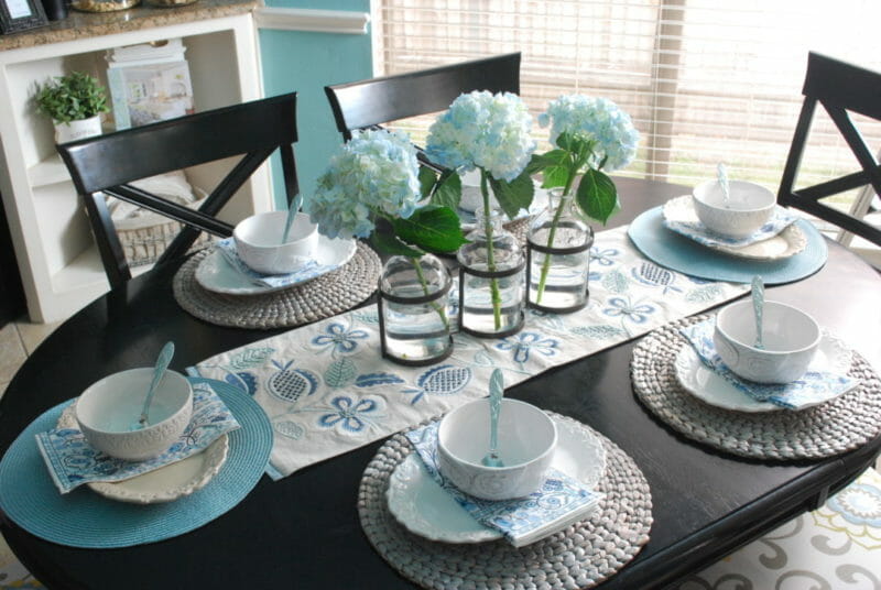 Blue and white tablescape using mismatached dishes with metal and glass floral vase for centerpiece