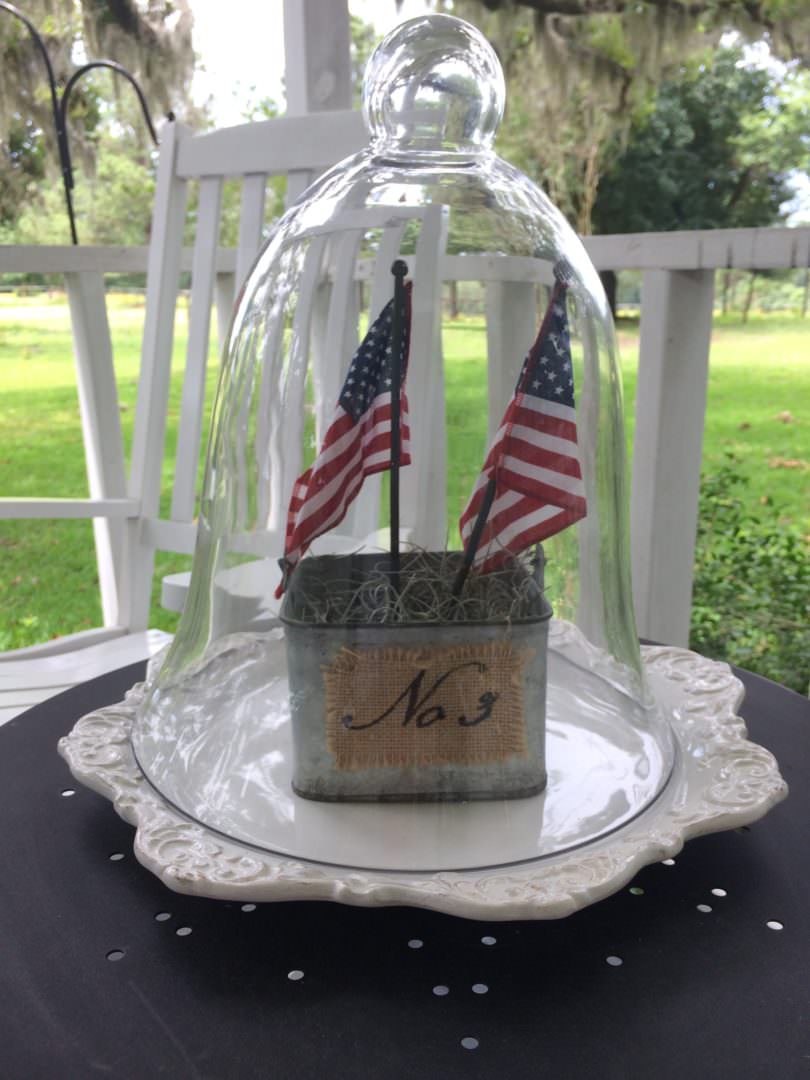 July 4th decor under a glass cloche on a farmhouse front porch