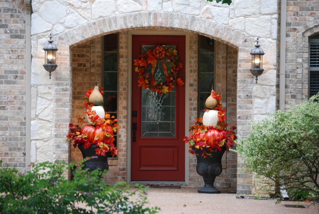 Pumpkin topiaries sitting on outdoor urns