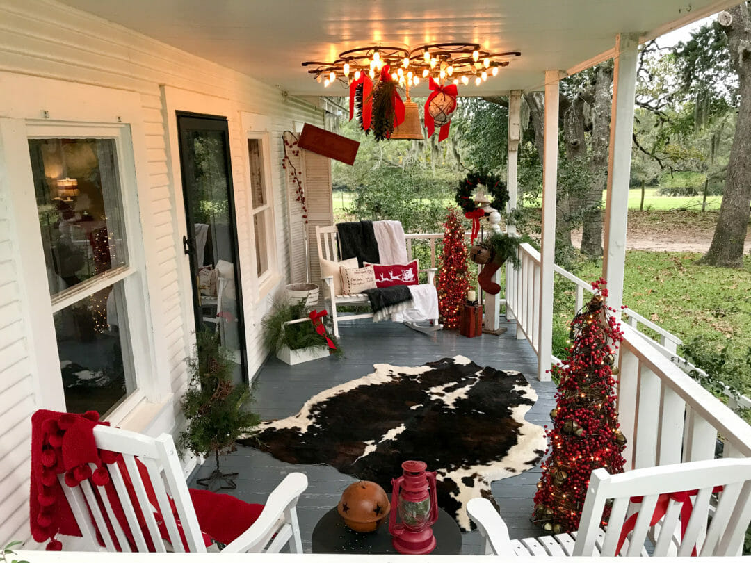 Christmas Farmhouse front porch with cow hide, red pillows and berry trees