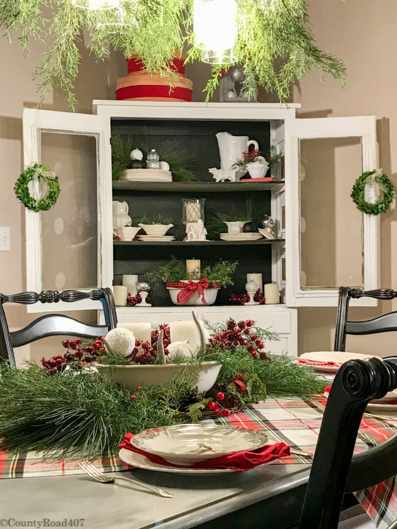 black and white hutch white china. Plaid tablecloth on the table with white bowl of berries and fresh greens