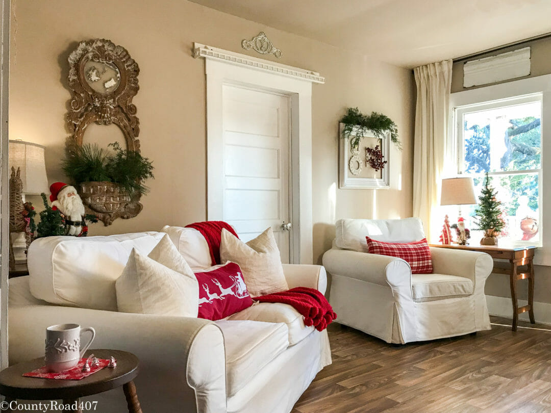 white sofa and chair with red pillows, fresh greenery hanging on wall decor