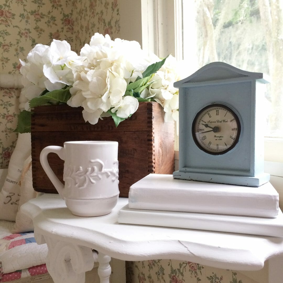 Vintage crate with flowers, clock and coffee cup on side table