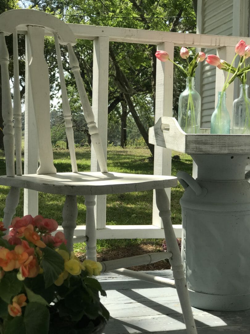vintage chair on porch with milk can side table and flowers