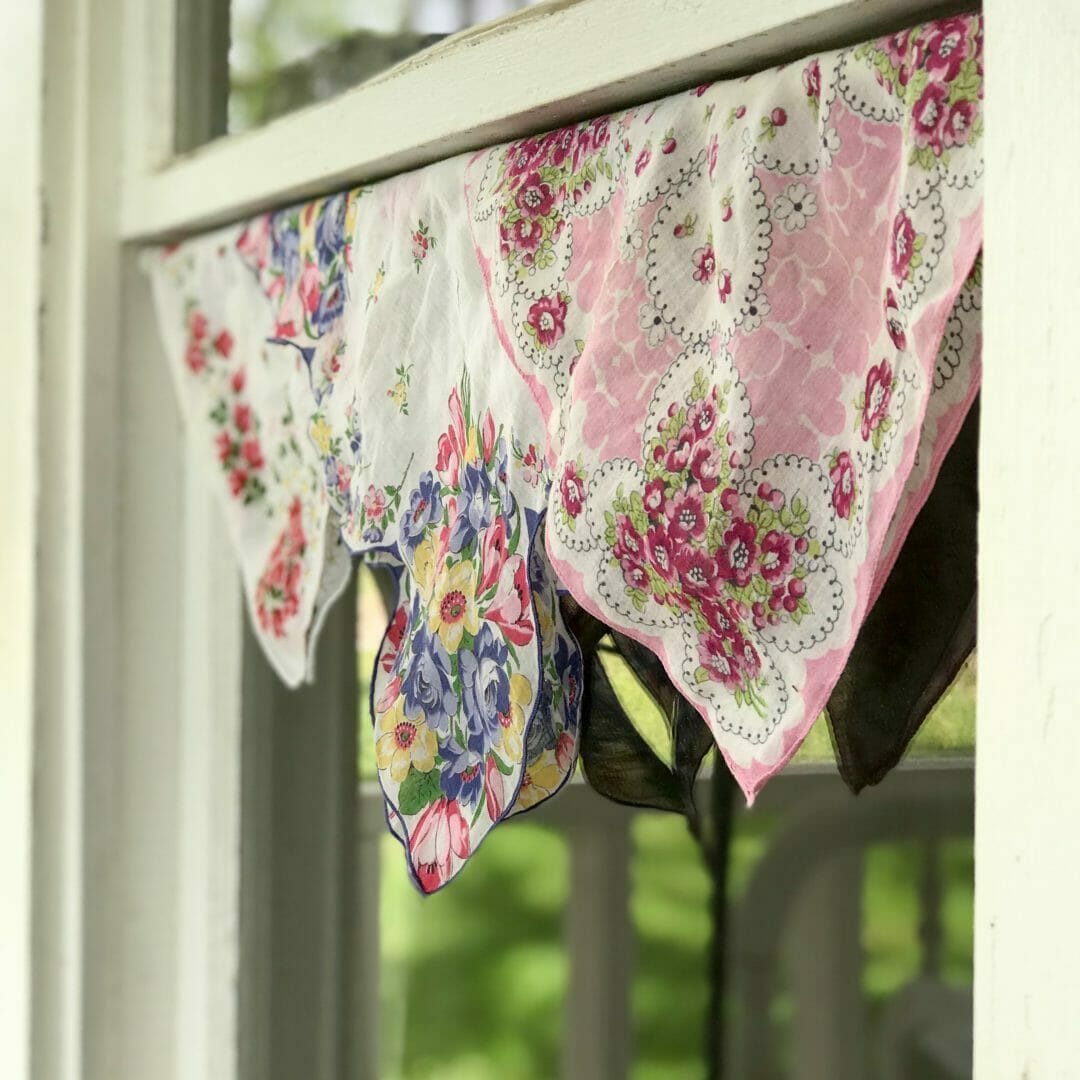 3 vintage handkerchiefs hanging in a window