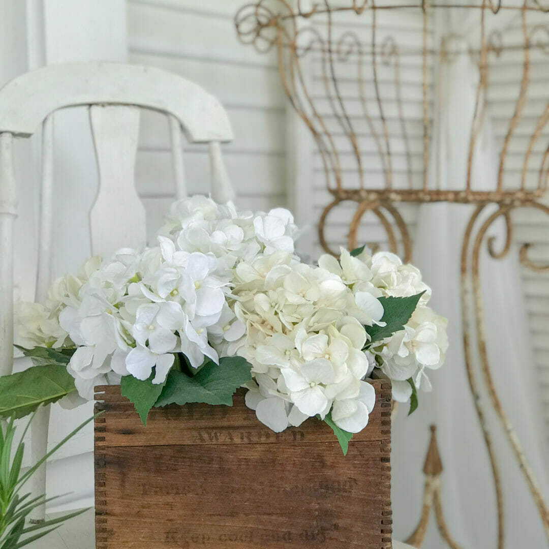 vintage crate with white hydrangeas and iron plant stand 