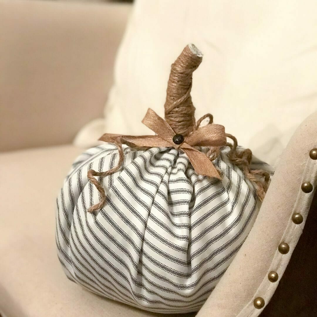 ticking striped fabric pumpkin with twine stem sitting in chair