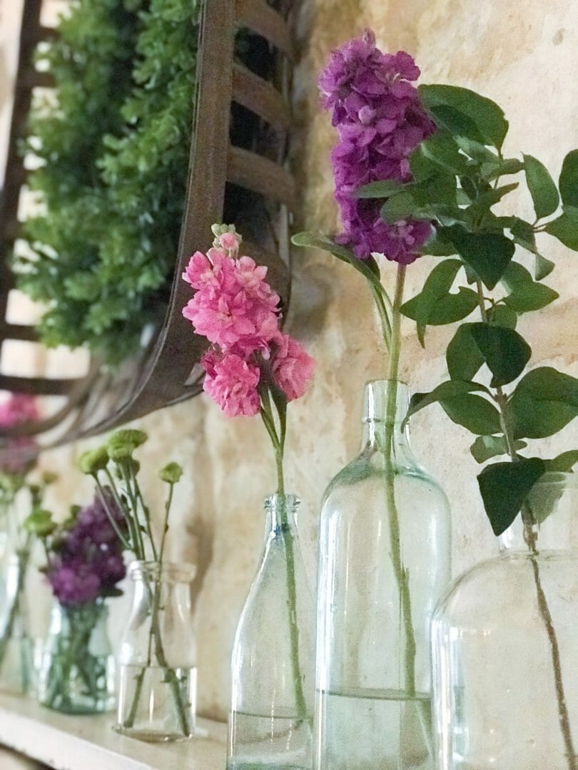 Spring mantel using vintage bottles by CountyRoad407.com #springmantel #springmantle #Springdecor #springdecorating #spring #decor #manteldecor #mantledecor #vintagebottles #bluebottles