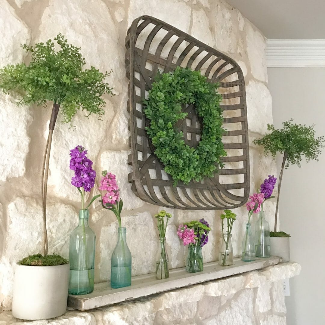 Spring mantel using vintage bottles by CountyRoad407.com #springmantel #springmantle #Springdecor #springdecorating #spring #decor #manteldecor #mantledecor #vintagebottles #bluebottles