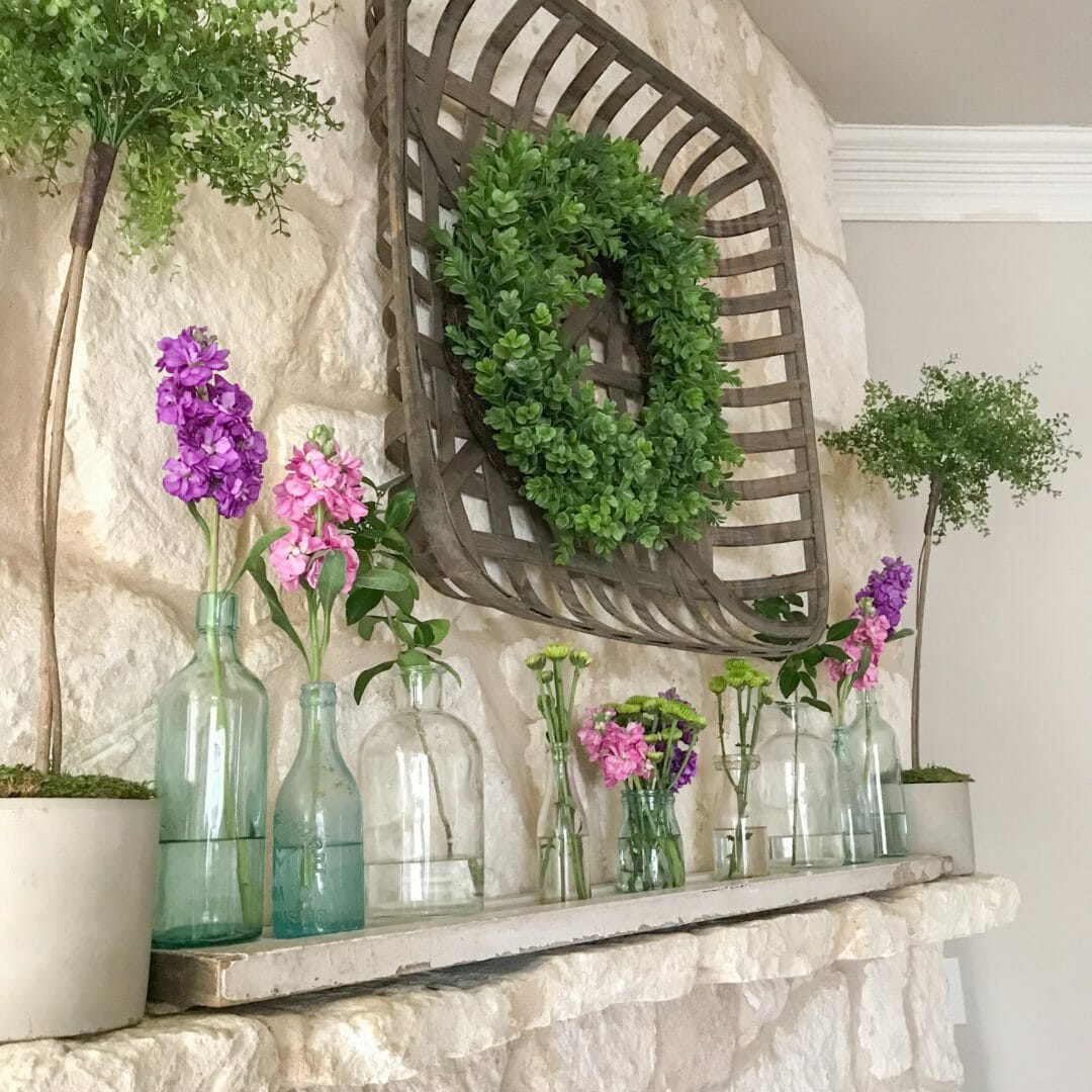 Spring mantel using vintage bottles by CountyRoad407.com #springmantel #springmantle #Springdecor #springdecorating #spring #decor #manteldecor #mantledecor #vintagebottles #bluebottles