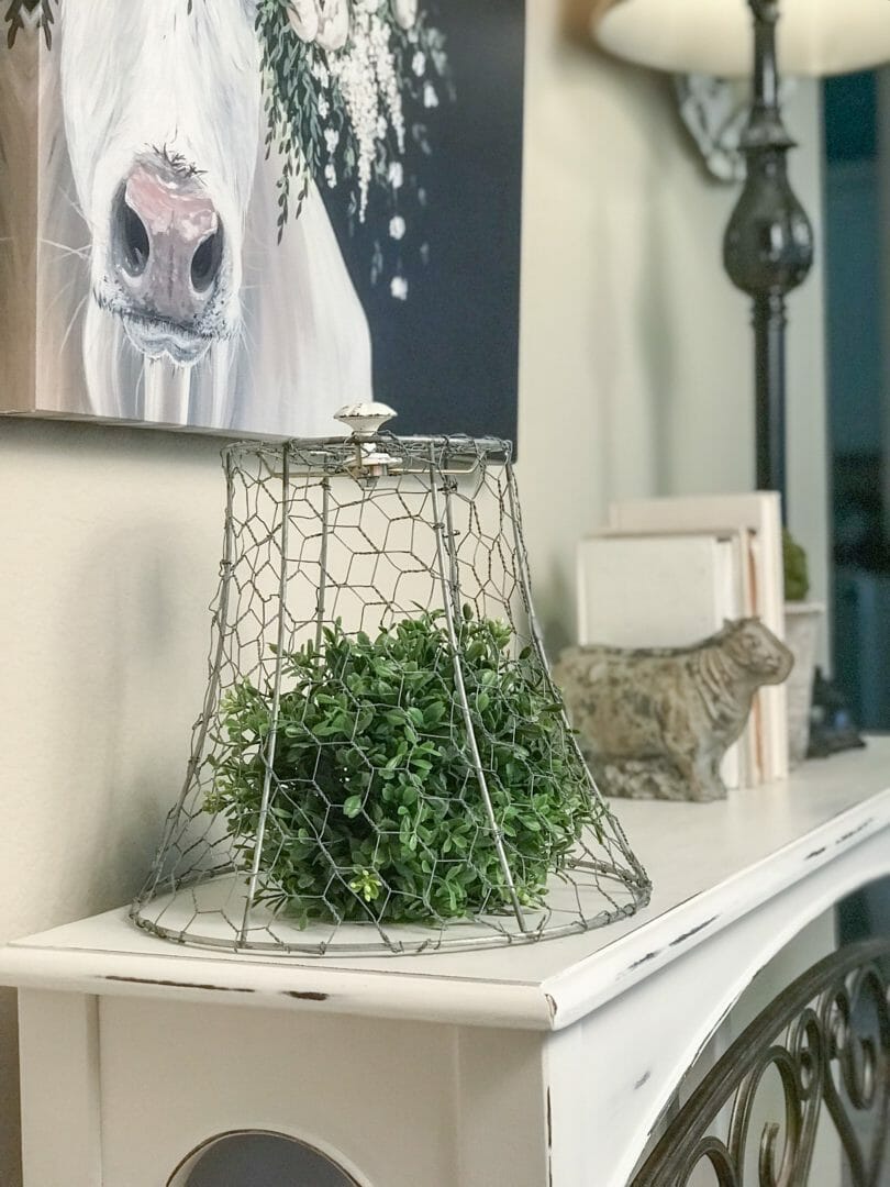 Chicken wire cloche with greenery ball on table