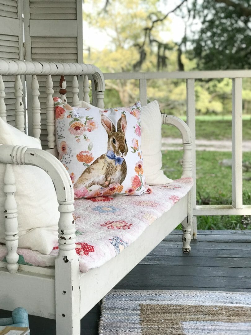 Spring porch with repurposed bed bench, spring bunny pillow and quilt.