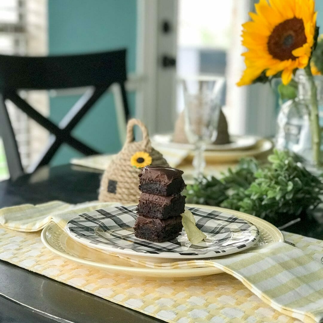 brownies stacked with potato chip on a black and white plate with yellow napkins