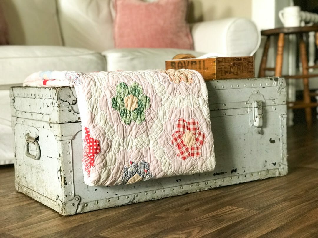 Vintage foot locker used as a coffee table. Old quilt hexagon flowers folded over edge