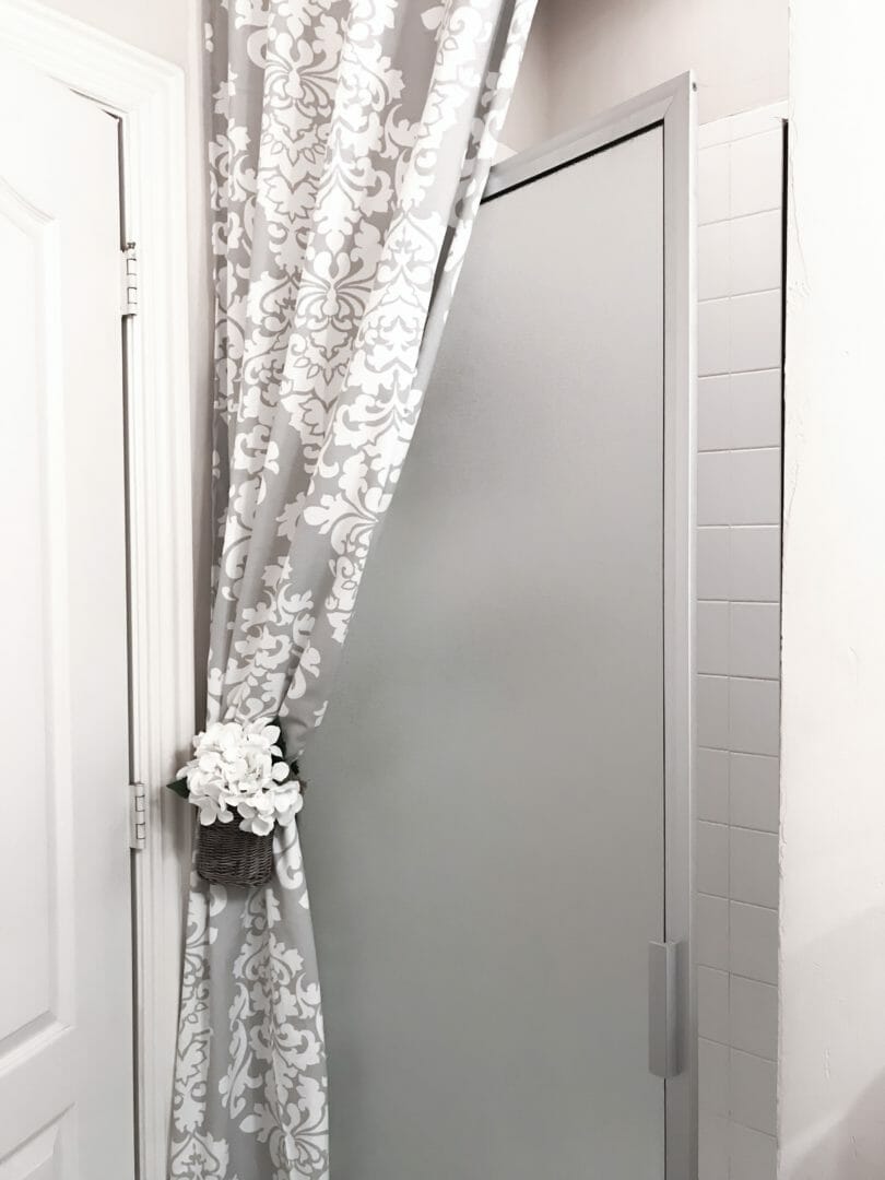 Shower door open with curtain and floral tie back basket