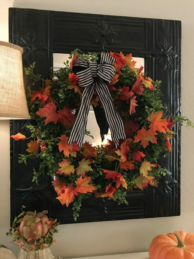 fall wreath with striped bow hanging on black mirror