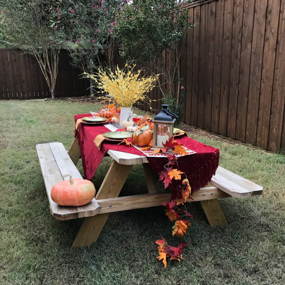 full view of picnic table with fall plates and pumpkins with garlend and floral arrangement