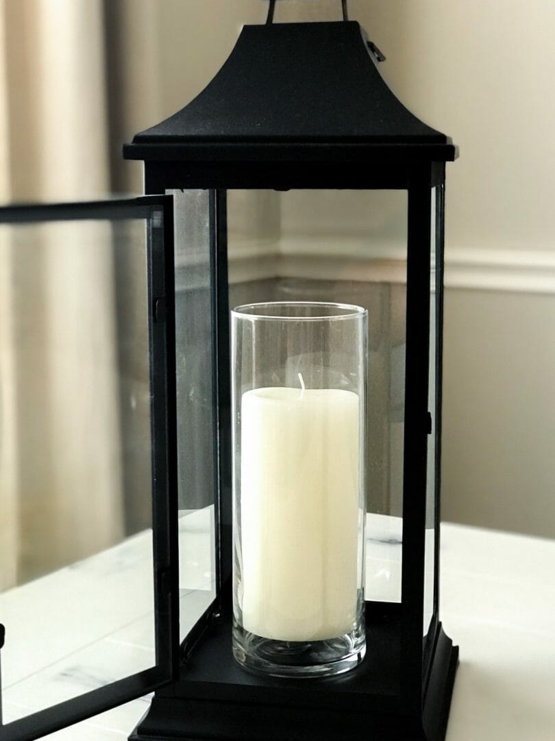 black lantern with white candle in glass jar