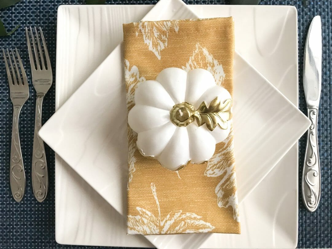 white plates with gold napkin and white pumpkin