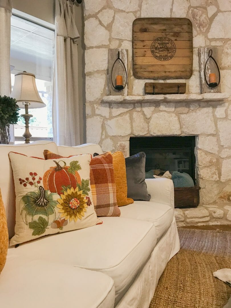 white sofa with pillows and stone mantel with iron sconces