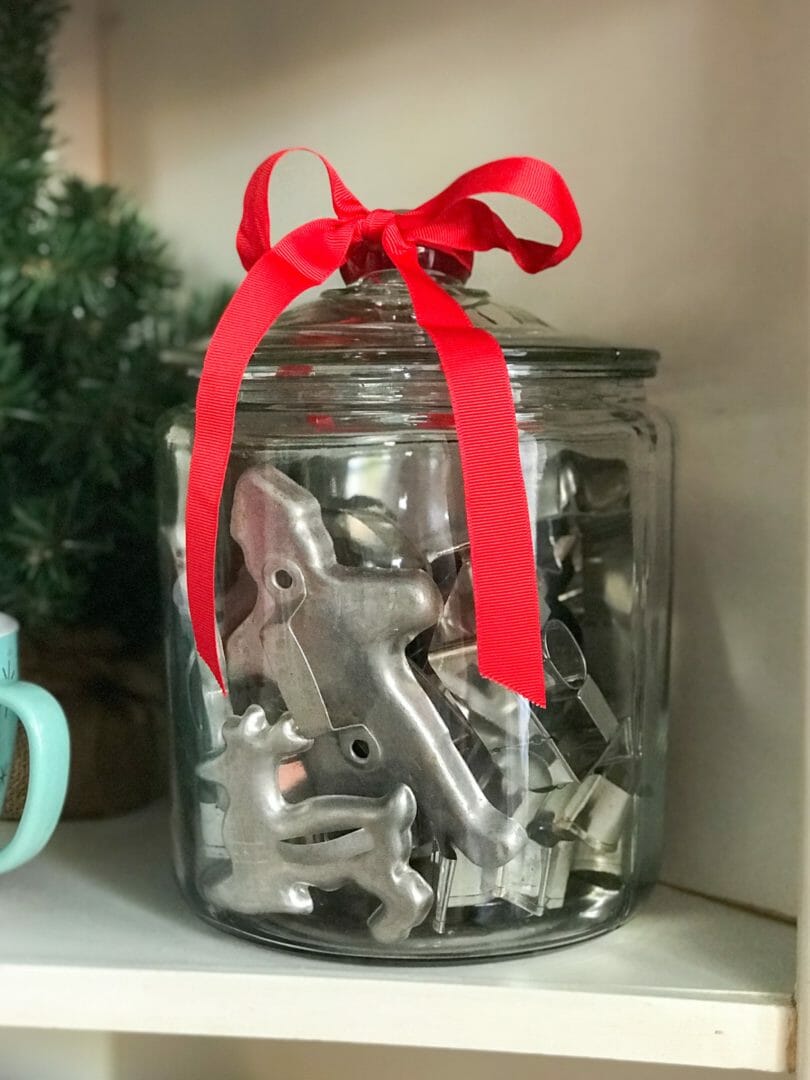 Glass jar with vintage cookie cutters and red ribbon