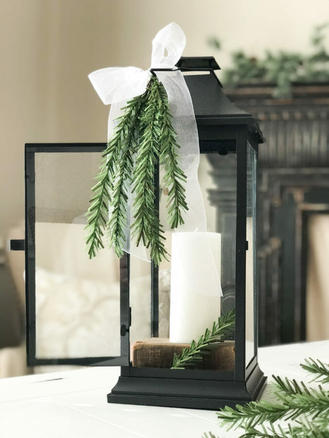 lantern with white candle and greenery stems