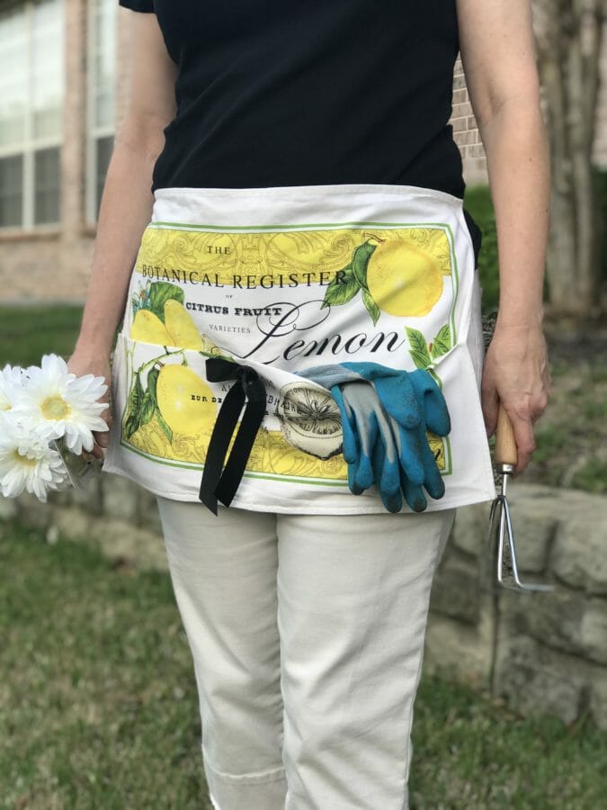 woman in gardening apron with flowers and tools