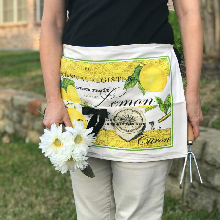 woman in gardening apron with flowers and tools