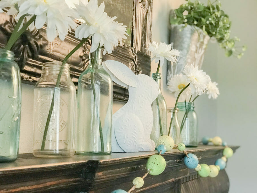 mantel with vintage bottles, flowers and bunny