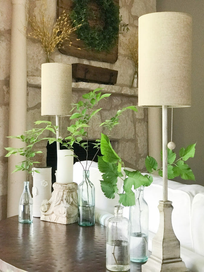 table with vintage bottles, greenery stems and lamps