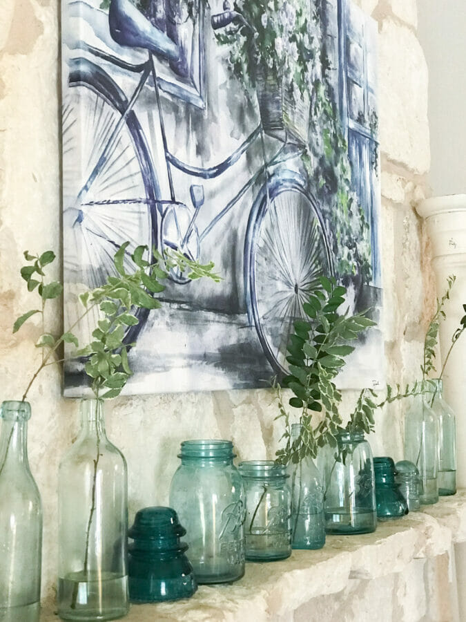 A refreshed summer mantel with artwork and blue bottles