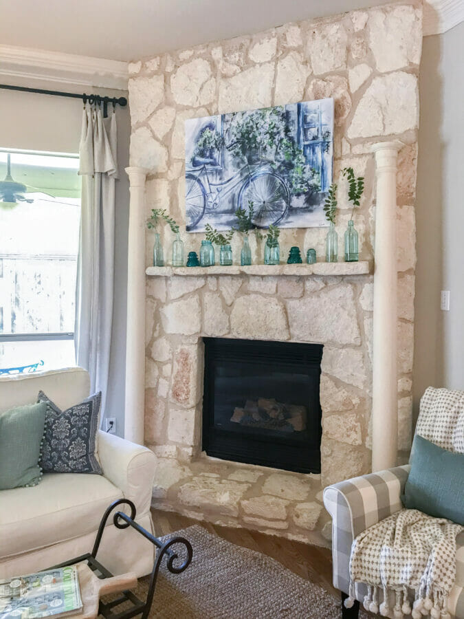 Stone mantel with columns, art work and vintage blue bottles