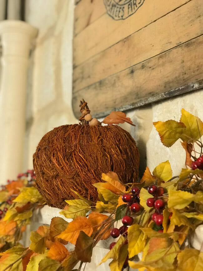 rust colored textured pumpkin on mantel with fall leaves and berries