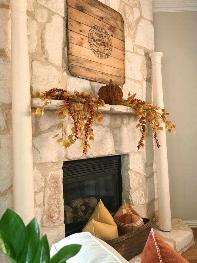 stone mantel with columns and fall stems and a single rust colored pumpkin