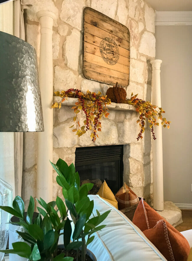 stone mantel with columns and fall decor with a plant in foreground