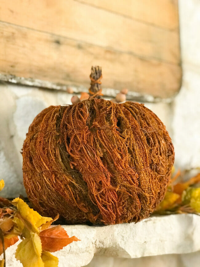 single heavily textured rust pumpkin sitting on mantel