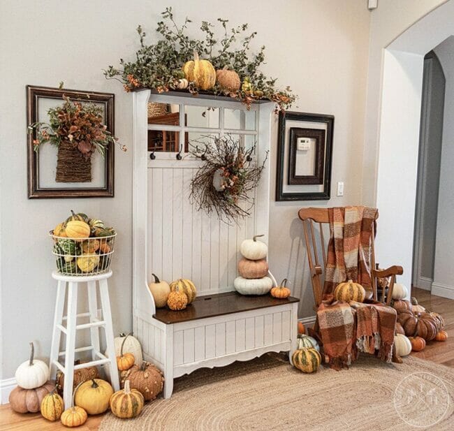 entryway with tall bench with fall decor. Pumpkins, stool, chair and blanket
