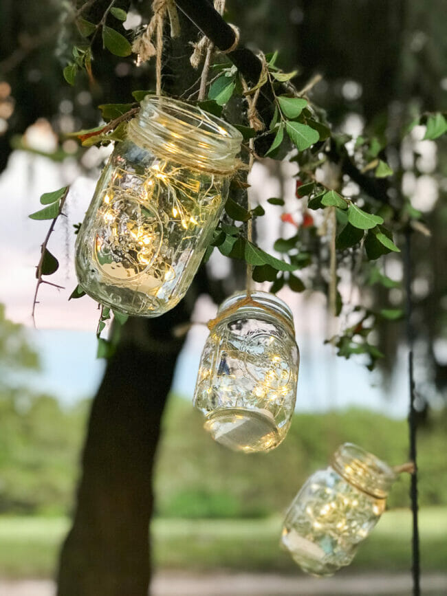 3 mason jars hanging from twine with trees in background