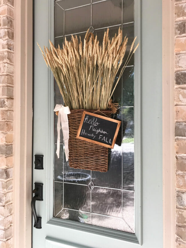 front door with hanging willow basket with wheat and chalkboard sign