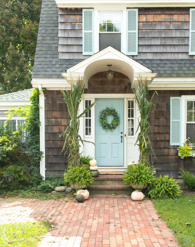 front door with wreath and cornstalks for fall decor