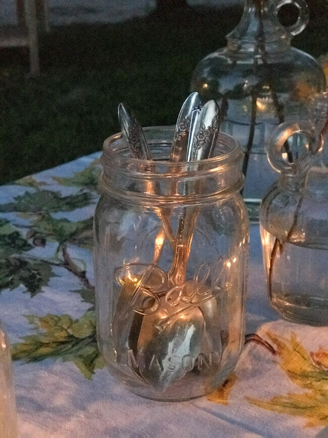 mason jar holding vintage spoons at an evening time outdoor table