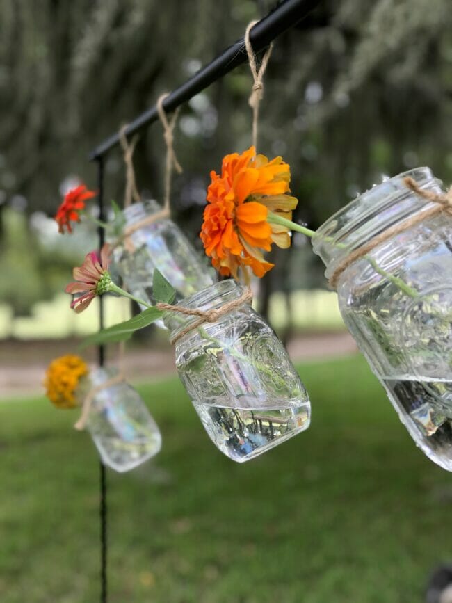 clear mason jars with flowers hanging from a table rod