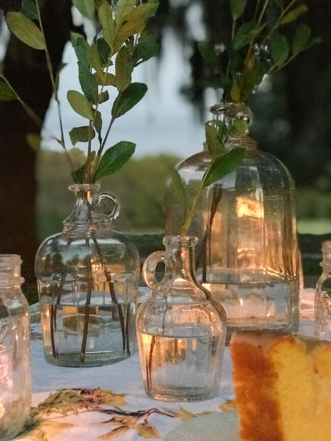 vintage bottles with fresh stems on an outdoor table with candles and cake