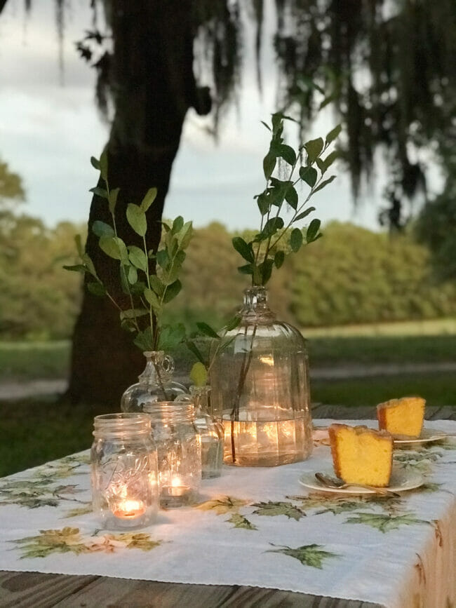 outdoor dining table with candles in jars and cake slices