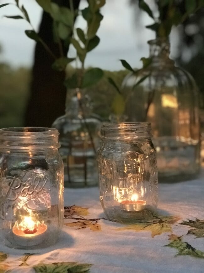 mason jars with tea lights and vintage bottles in back ground