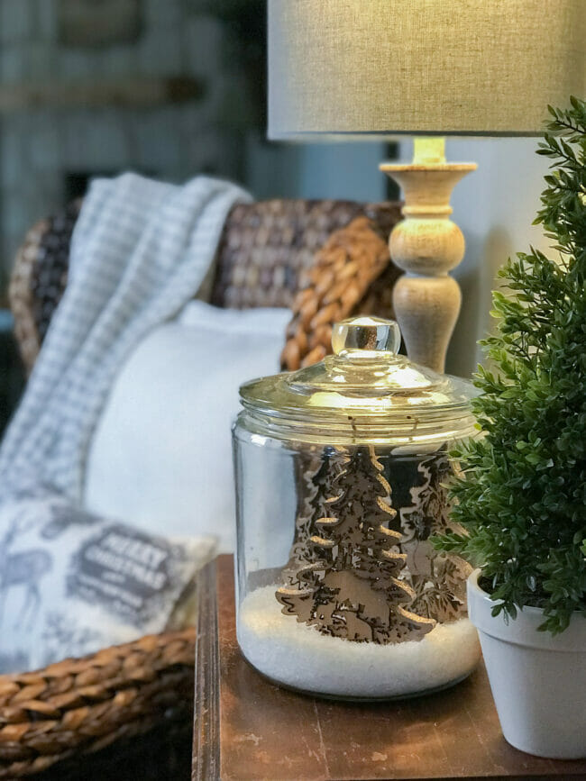 Jar with Christmas ornaments of wooden forest and chair with pillows