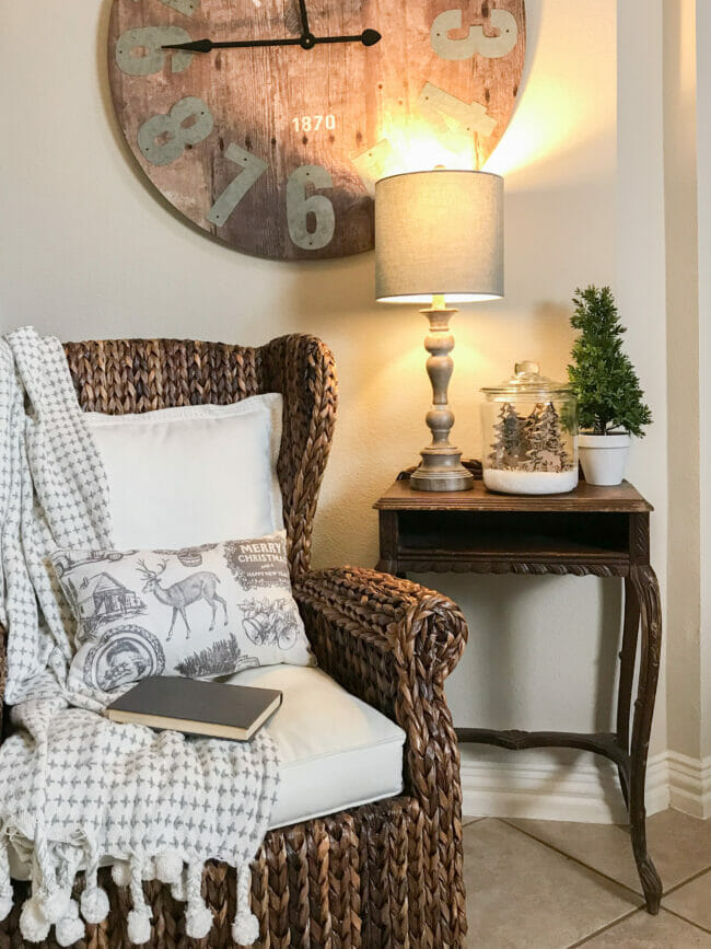 rattan chair with blanket, pillow, lamp, plant and rustic jar