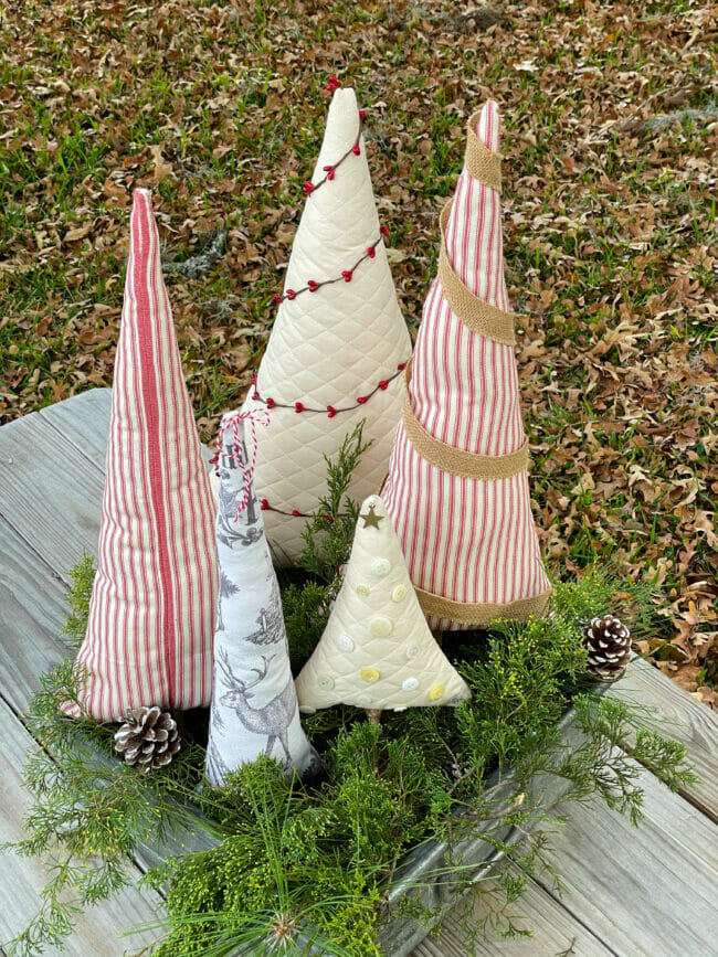 higher view of fabric Christmas trees in crate with greenery stems