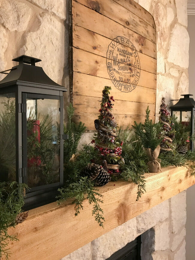 finished wood mantel with Christmas greens and lantern