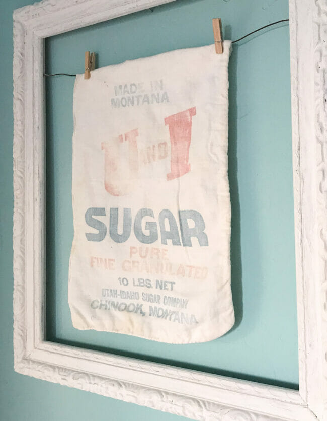 sugar sack with clothes pins on line in white frame